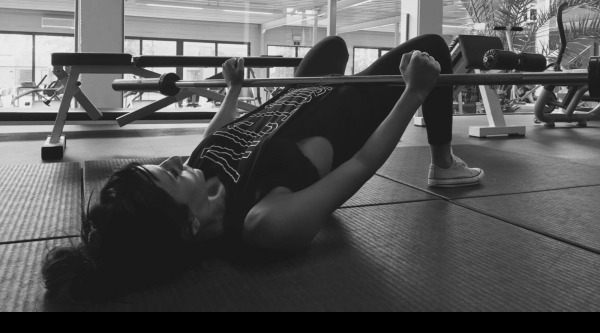 photo of a female performing a hip bridge exercise with a barbell