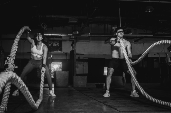 2 sporters die aan het trainen zijn met een battle rope
